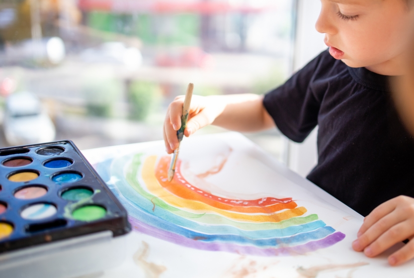 boy-draws-with-multicolored-paints-paper-rainbow-sitting-table-home-closeup-view