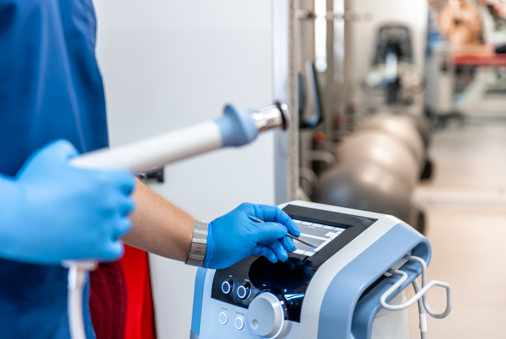 shock-wave-therapy-device-with-male-doctor-hands-rubber-gloves